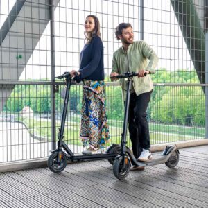 brücke über einen fluß mit zwei personen die ihren scooter schieben